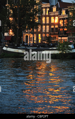 Abendlicht spiegelt sich in den Fenstern und das Wasser des Kanals, Amsterdam, Niederlande Stockfoto