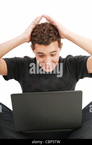 junger Mann schockiert mit etwas, das er auf seinem Laptop zu sehen Stockfoto