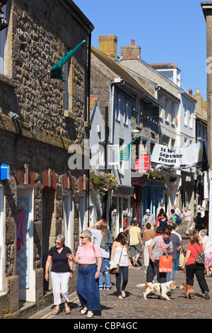 Geschäfte auf einer schmalen gepflasterten Straße voll von Touristen in St. Ives, Cornwall, England, Vereinigtes Königreich, Großbritannien. Stockfoto