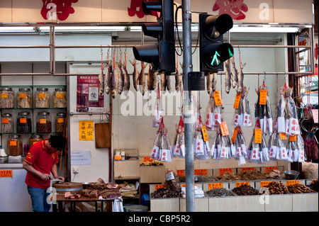 Westlicher Bezirk auf Hong Kong Island hat noch viele traditionelle Geschäfte und Straßen. Fische trocknen hinter Ampel. Stockfoto