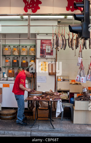 Westlicher Bezirk auf Hong Kong Island hat noch viele traditionelle Geschäfte und Straßen. Fische trocknen hinter Ampel. Stockfoto