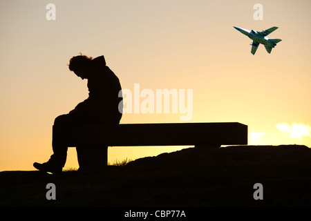 Ein Mann sitzt auf einem Denkmal Sitz auf Orrest Head oben Windermere im Lake District, Cumbria, England. Stockfoto