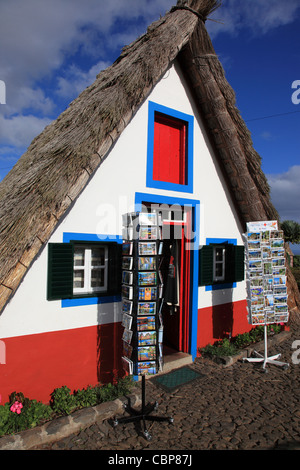 Postkarten zum Verkauf vor einem traditionellen dreieckigen Haus Santana Madeira Portugal Europa. Foto: Willy Matheisl Stockfoto