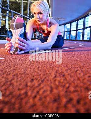 Frau erstreckt sich in der Vorbereitung für Training Stockfoto