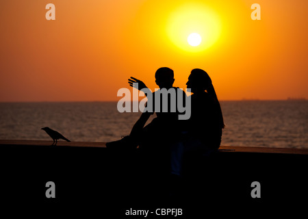 Junge indische Paare sitzen am Deich bei Sonnenuntergang am Nariman Point, Mumbai, ehemals Bombay, Indien Stockfoto