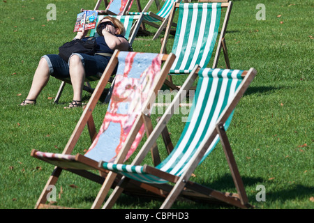 Frau lesen Buch im Liegestuhl St James Park in London England Stockfoto