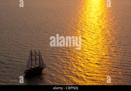 Großen maskierte Segelboot segeln in den Sonnenuntergang in der wunderschönen Oia in Santorini Griechenland Griechische Inseln von oben auf Klippe ins Wasser Stockfoto