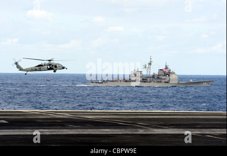 ATLANTISCHER OZEAN (Dez 9, 2011) ein MH-60S Sea Hawk, der Helicopter Sea Combat Squadron (HSC) 9 zugewiesen wurde, führt neben dem Flugzeugträger USS George H.W. einen Vorbeiflug des Lenkraketen-Kreuzer USS Anzio (CG 68) durch Buchse (CVN 77) während einer Luftkraftdemonstration. George H.W. Bush beherbergt mehr als 1,200 Freunde und Familienmitglieder der Crew als Teil einer Tiger Cruise am Ende des ersten Kampfeinsatzes von shipÕs. Stockfoto