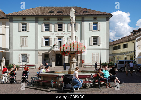 Rathaus von Kaltern an der Südtiroler Wein-Route mit dem Marienbrunnen auf dem Marktplatz. Stockfoto