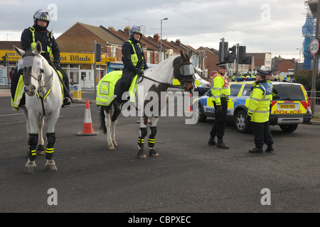 Berittene Offiziere und Fuß Polizei blockieren eine großen Straßenkreuzung während ein Fußball-Spiel-Gruppenkontrolle. Portsmouth (Hampshire). Stockfoto