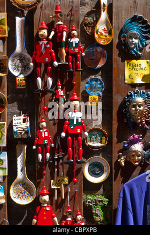 Touristische Objekte einschließlich Pinocchio Holzfiguren hängen auf dem Display außerhalb einer Ladenzeile in Siena, Italien. Stockfoto