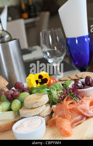 Geräucherter Lachs mit schwarzen Oliven, Trauben & Salat in einem Restaurant Ambiente Stockfoto