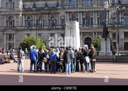 Eine Reisegruppe und Reiseführer auf dem George Square im Stadtzentrum von Glasgow, Schottland, Großbritannien Stockfoto