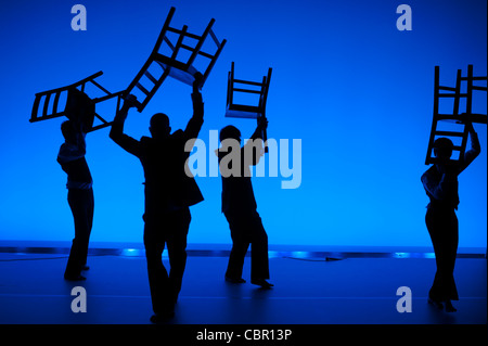 Silhouette Aberystwyth University Studies Theaterstudenten Durchführung einer ausgearbeiteten improvisiert Tanzstück hält Stühle UK Stockfoto