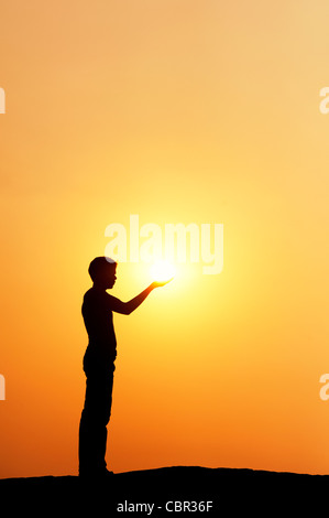 Indischen Mann stand halten die Sonne. Silhouette. Indien