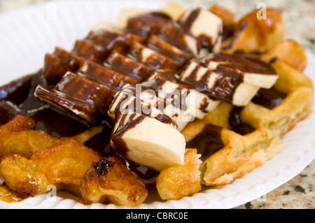 Horizontale Nahaufnahme von einer frisch gekochten Liège Waffel erstickt in in Scheiben geschnittenen Bananen und Schokoladensauce. Stockfoto