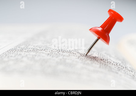 Nahaufnahme von einer roten Reißzwecke stecken in einem Buch Stockfoto