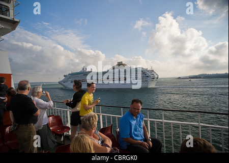 Passagiere auf einem Isle Of Wight-Autofähre gerade ein großes Kreuzfahrtschiff passieren auf dem Solent in der Nähe von Southampton, UK Stockfoto