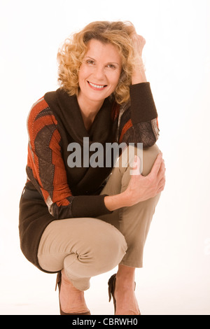 modische ältere Frau sitzt in einer hockenden position Stockfoto