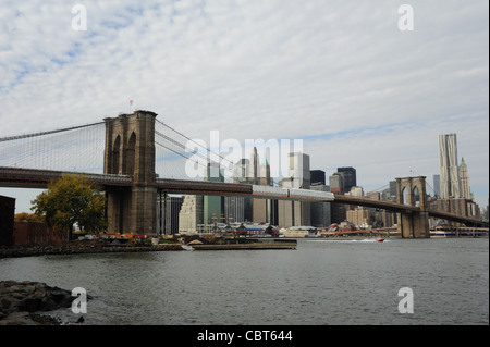 Herbstliche Ansicht East River Brooklyn Bridge in Richtung Pier 17 und Manhattan Wolkenkratzer von Fulton Ferry Park, Brooklyn Dumbo, NY Stockfoto