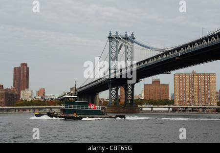 Schlepper auf grauen Gewässern East River, südlich von Manhattan Bridge Mid-Span, in Richtung Manhattan aus Brooklyn Fulton Ferry Park Stockfoto