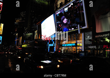 Nächtliche Schrägansicht Verkehr beleuchtet Scheinwerfer vorne Neon LED Fassaden Disney Store, Forever 21, 7th Avenue, New York Stockfoto