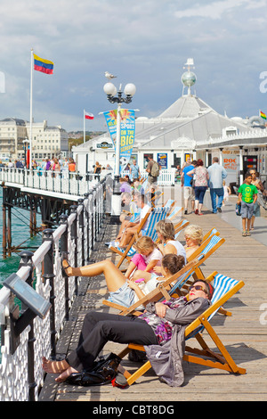 Menschen auf Urlaub und Ferien sitzen, entspannen, Wandern und Vergnügen sich auf der Pier von Brighton Promenade. Stockfoto