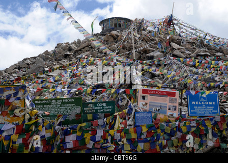 Gebetsfahnen und Zeichen an der Spitze der was behauptet, der weltweit höchste befahrbare Straße passieren, Khardung La. Stockfoto