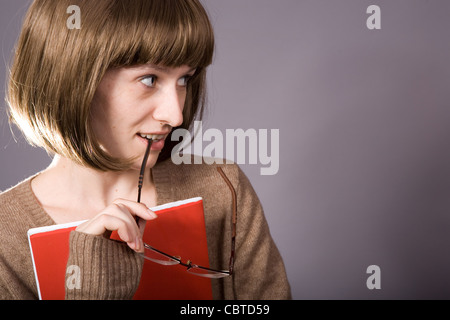 Eine Mädchen (Lehrer oder Schüler) sieht mit Interesse entgegen. Gläser und rot-Datei in ihren Händen. Stockfoto