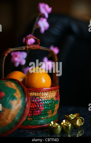 Korb mit Orangen mit Goldbarren und Pflaumenblüte Stockfoto