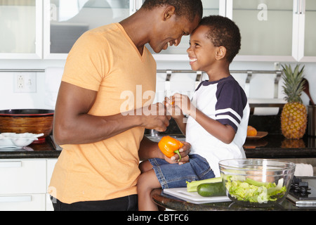 Afroamerikanischen Vater und Sohn machen Salat in Küche Stockfoto