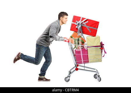 Junger Mann läuft und schob einen Einkaufswagen mit Geschenken Stockfoto