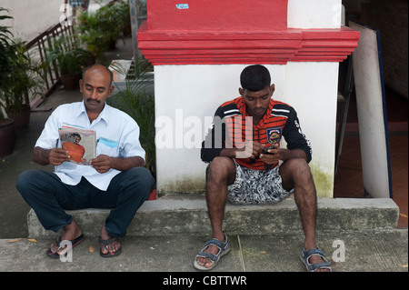 Zwei Männer sitzen auf Bürgersteig, Little India, Singapur Stockfoto