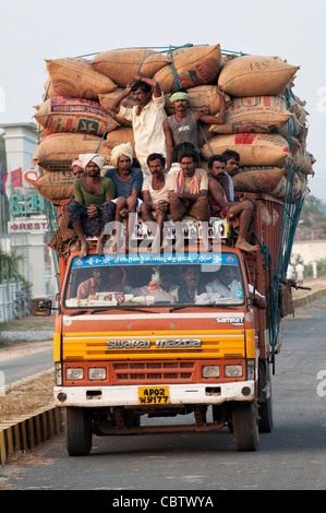 Überladene indische LKW tragen Säcke mit Reis und landwirtschaftlichen Arbeitern. Andhra Pradesh, Indien Stockfoto