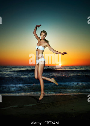 Kaukasische Frau springen am Strand Stockfoto