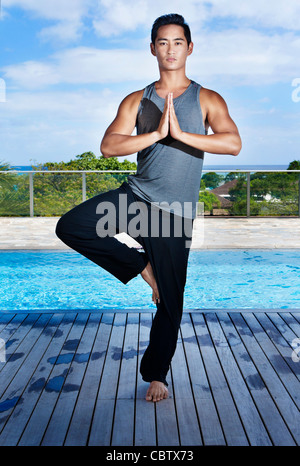 Asiatischer Mann praktizieren Yoga am Pool Stockfoto
