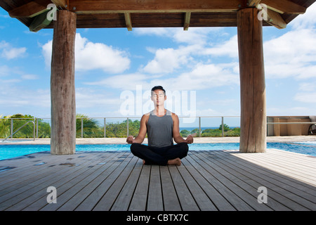 Asiatischer Mann praktizieren Yoga am Pool Stockfoto