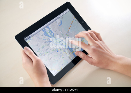 Frau Hände halten und auf Apple iPad2 mit Google Maps-Anwendung auf einem Bildschirm zu berühren. Stockfoto