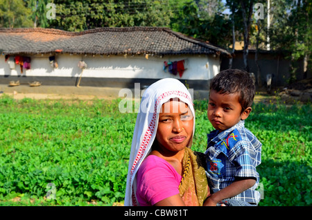 Glückliche indische Farmerin in Sari mit einem Kleinkind Jungen Vor ihrem Haus auf dem Bauernhof in einem hellen stehen Sonniger Morgen Stockfoto