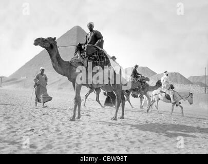 Ägypten. Pyramiden von Gizeh. Kamele & Fahrer in der Nähe der großen Pyramide geschaffen zwischen 1934 und 1939 Stockfoto