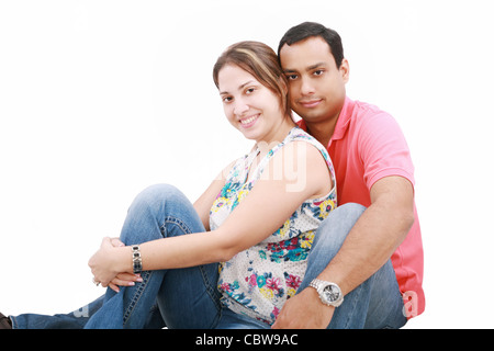 glückliches Paar sitzen neben Wand lächelnd Stockfoto