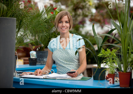 Porträt eines glücklichen Gewächshaus Mitarbeiters in ein Tagebuch zu schreiben und in die Kamera schaut Stockfoto