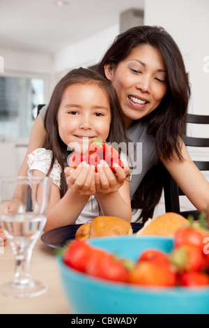 Lächelnde Mutter und Tochter mit frisch gepflückten Erdbeeren Stockfoto