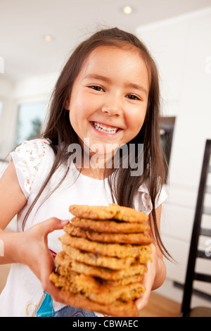 Glücklich, lachen und Lächeln junge süße Mädchen Holding Stack von große hausgemachte cookies Stockfoto