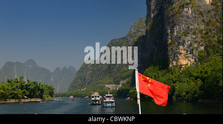 Panorama der chinesischen Flagge und Kreuzfahrtschiffe und Sightseeing Flöße auf dem Lijiang-Fluss Guangxi Peoples Republic Of China mit hohen Karstgebirge Stockfoto