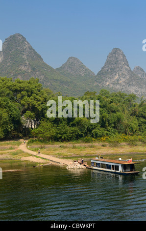 Landwirte, die Güter zu einem Bambus raft mit verrosteten Kahn und Karst Peaks auf Li-Fluss Peoples Republic Of China Stockfoto