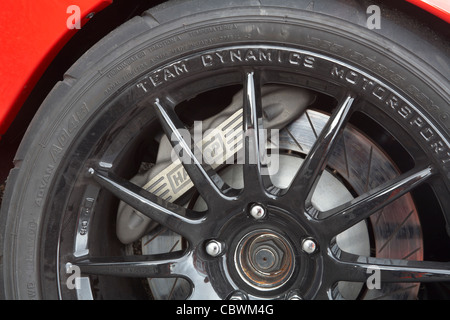 Bremssattel Bremszange und Scheibe Bremsscheibe hinter Metalllegierung Radspeichen auf einem Stromkreis-Rennwagen. Stockfoto