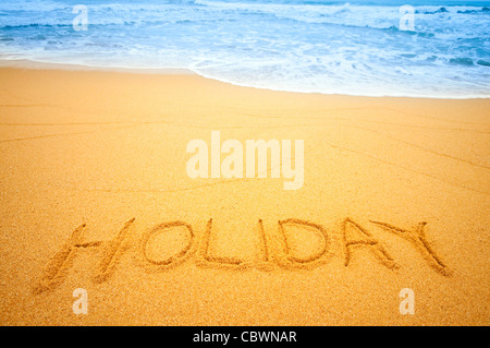 "Urlaub" in den Sand am Strand blauen Wellen im Hintergrund geschrieben Stockfoto