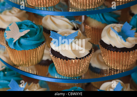 Kleine Kuchen mit Creme Sahnehäubchen und Schmetterling Stil Dekorationen Stockfoto