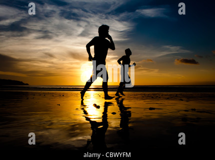 Zwei Männer Schatten laufen am Strand bei Sonnenuntergang Stockfoto